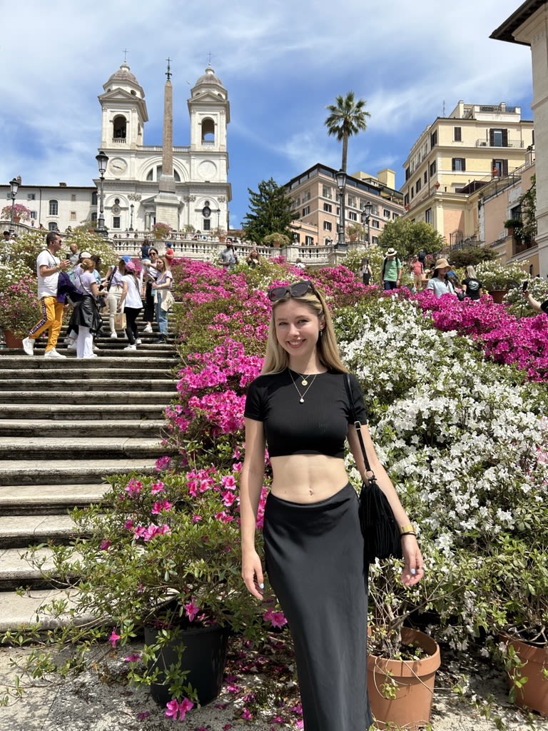 Lily-May stood in front of beautiful pink and white flowers and old Italian steps