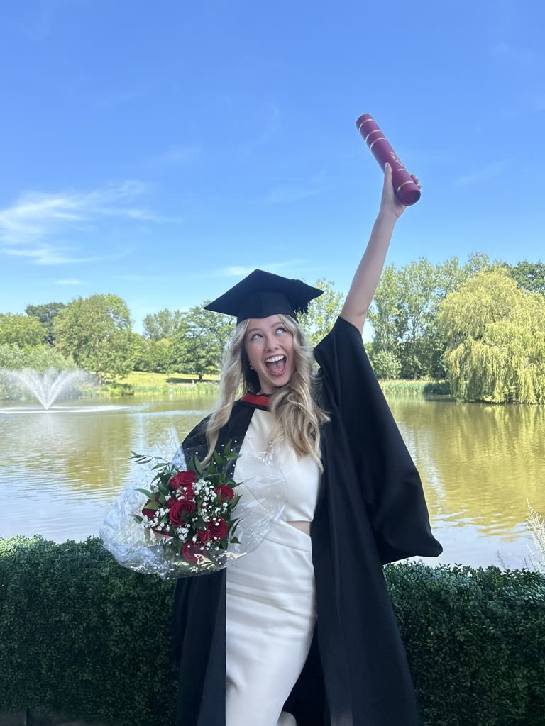 Lily-May at graduation with her arm in the air in celebration
